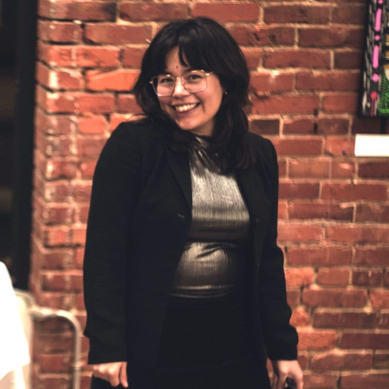 Lidia smiles in a black blazer at her Our Light Unbound art exhibition.