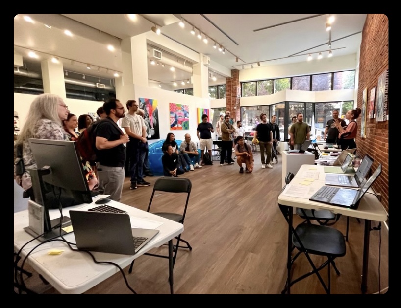 Attendees gathered in a gallery space during the Seattle AI on Tap Gallery Walk, watching a presenter demo a project