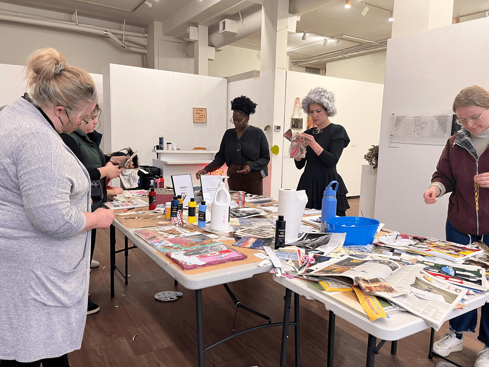 Participants at the closing event art activism workshop gathered around a table with collage materials, creating artwork together