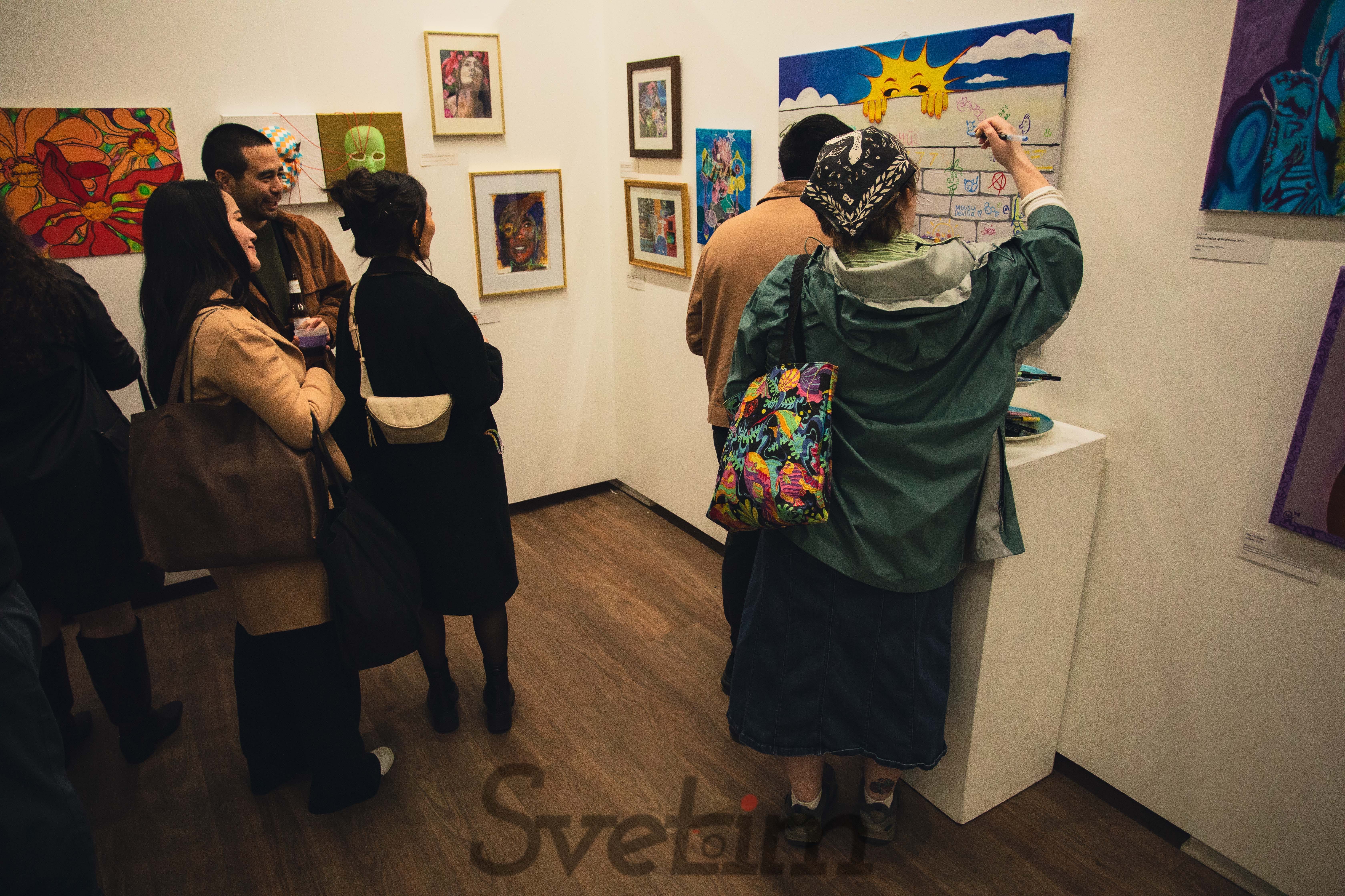 Visitors engaging with artwork and interactive installations, gathering around pieces and discussing them with each other